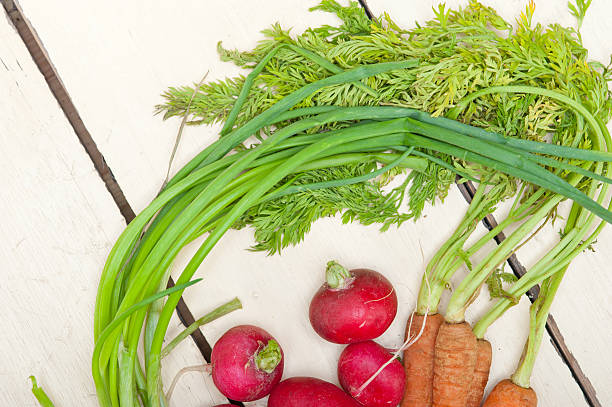 Spring vegetables including asparagus, peas, and radishes on a wooden table